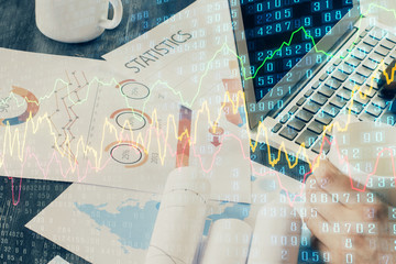 Double exposure of stock graph with businessman typing on computer in office on background. Concept...
