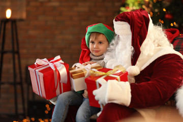 Fototapeta na wymiar Santa Claus and little boy with Christmas gifts indoors