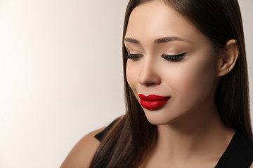 Fototapeta premium Beautiful woman with red lipstick on light background, space for text