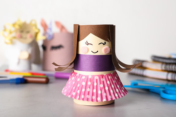 Toy doll made of toilet paper hub on grey table