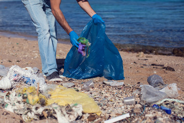 Man volunteer with big bag for trash collecting garbage on beach. Environmental pollution concept