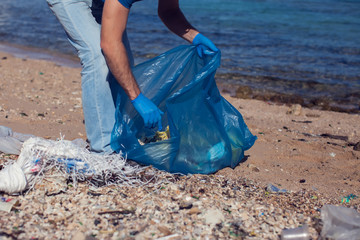 Man volunteer with big bag for trash collecting garbage on beach. Environmental pollution concept