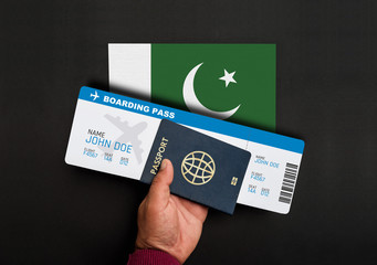 Hand holds passport and boarding pass with flag of Pakistan