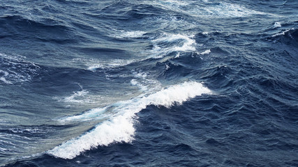 Naklejka premium Sea ​​waves in the storm. dark blue water of the Pacific Ocean, white foam on the waves. pure salt water texture