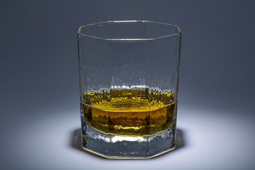 A glass of whiskey with ice. Art installation with lighting from above and close-up.