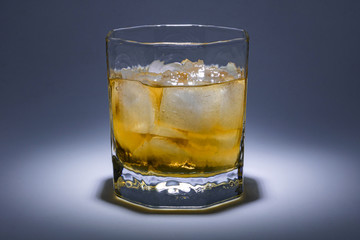 A glass of whiskey with ice. Art installation with lighting from above and close-up.