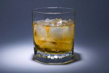 A glass of whiskey with ice. Art installation with lighting from above and close-up.