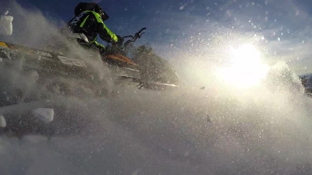 riding with jumps on mountain snowmobiles on fresh snow with swirls and splashes. snow motorcycles and winter tourism. snowmobile outdoor activities