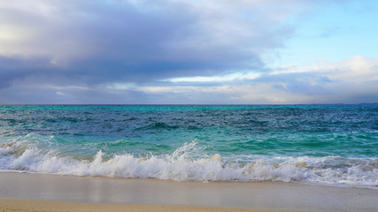 Tropical beach white sand, blue clear ocean water. sea ​​foam on the beach on a sunny day. sea waves on the shore. surf breaking on shore at sunset