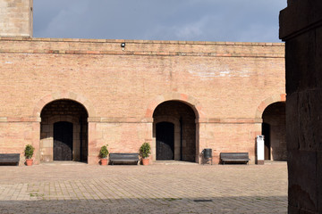 Arched Stone Entrances & Wooden Benches in Old Sunny Courtyard 