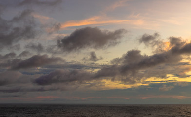 Naklejka na ściany i meble A dramatic set of clouds, at sunset, drifting over the tropical waters of the Caribbean Sea are lit by the last moments of daylight.