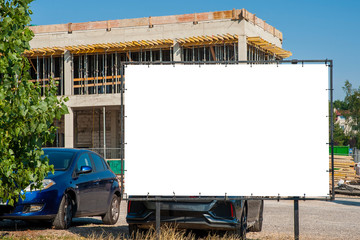 Blank white billboard for advertisement in the front of construction site on a sunny day.