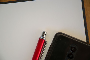 Mobile phone on top of a notebook, black background, business concept, copy space