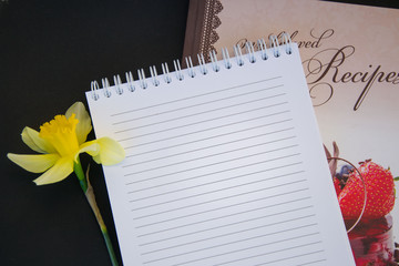 Naklejka premium Fresh spring yellow daffodil flower, empty textbook paper with empty place for text, copy space, romantic concept, black background