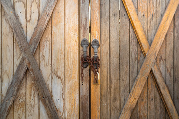 Vintage wooden farmhouse gate/door with chain locked. Countryside building or background textured photo.