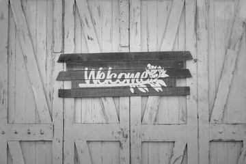Close up at pattern of white old-style wooden door which is has "Welcome" text sign plate on it. Background/texture photo, Selective focus.