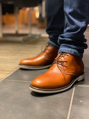 Man wearing blue jeans and pair of brown shoes
