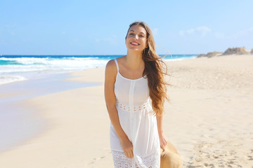 Fototapeta na wymiar Portrait of beautiful smiling woman with white sundress walking on sand in empty wild beach on Canary Islands