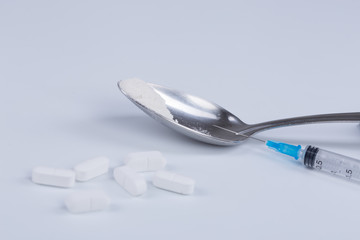 White pill, syringe and heroin on spoon. Drug addiction.