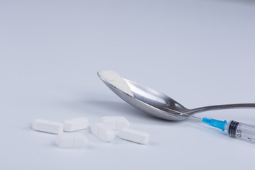 White pill, syringe and heroin on spoon. Drug addiction.