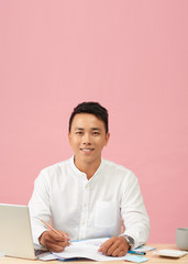 Young attractive asian businessman using laptop sitting on desk table in office