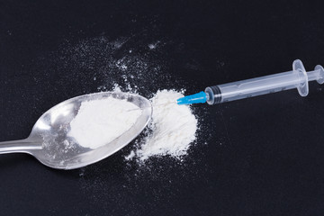White pill, syringe and heroin on spoon. Drug addiction.