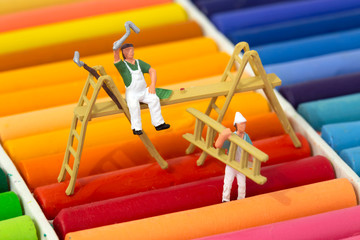Miniature scale model painters and decorators with ladders on a set of oil pastel crayons.  Decorating concept