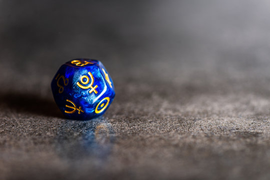 Blue Astrology Dice with symbol of the planet Pluto on grey background