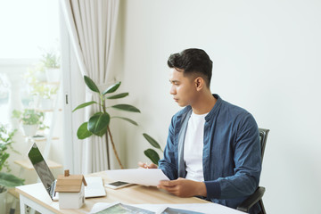 Young engineer. Successful busy man drawing something while working in the office