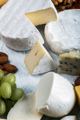 many different types of cheese with nuts, grapes and dried fruits