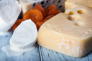 types of different cheese mozzarella, brie, Roquefort, Maasdam, etc. on the table with nuts