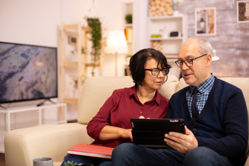 Beautiful old couple using a digital tablet to chat with their family