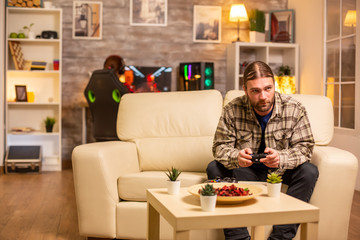 Male gamer playing video games on a console in the living room