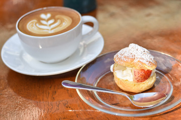 Strawberry chu cream recipe in aplate with latte coffee cup in the background.