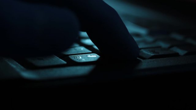 Close up of typing on laptop keyboard in the darkness.