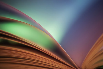 Book pages close up on a blue background. Macro photography in blue green colors is suitable as a background on the topics of reading, literature, book business, book publishing.