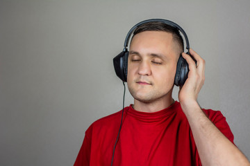  young guy in red t-shirt listening to music in headphones