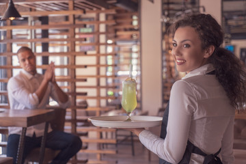 Waitress holding cocktails in a cafe shop