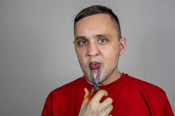 a young guy in a red T-shirt cuts his tongue