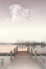 travel photography, misty morning landscape side view with a river, a pier and a large cloud in pastel colors close up