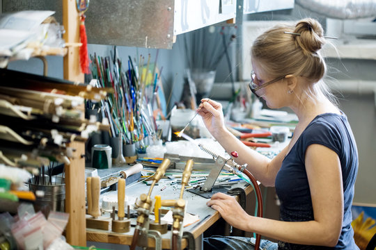 Woman artist making glass jewelry in her workshop