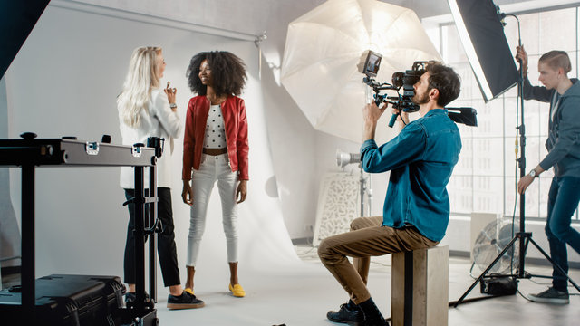 Cameraman Filming Make-up Artist Applies Makeup to a Beautiful Black Model. They Pose for a Video Clip. Stylish Fashion Magazine. Photo Shoot done with Pro Equipment in a Studio