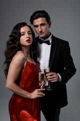 Romantic festive couple holding glasses of champagne, isolated on grey