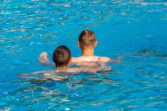Two guys swim in the pool, summer vacation at the resort_