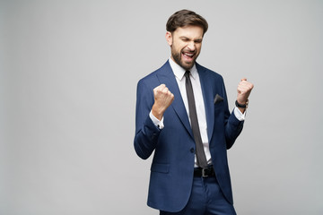 Very happy successful winner gesturing businessman over grey background