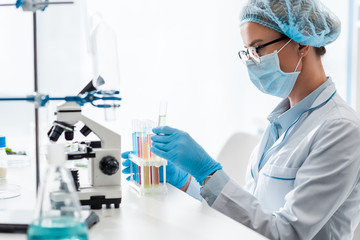 Fototapeta premium side view of biologist looking at test tube in lab