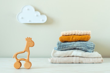 Fototapeta na wymiar Wooden toys giraffe and organic cotton baby clothes on the shelf