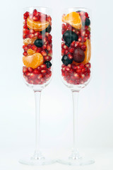 two glasses filled with fruit on a light background