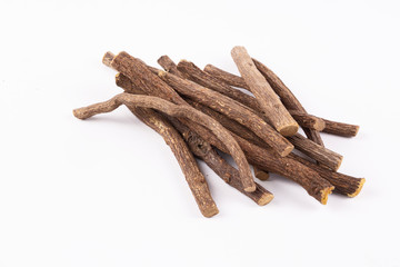 Macro closeup of a traditional sweet heap pile of Liquorice licorice wooden wood roots sticks spice isolated on white