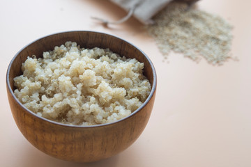 Cooked quinoa in wooden bowl  on  brown background